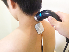 男性患者の首に超音波・ハイボルテージコンビネーション治療器を当てるようす
